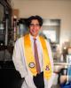 Sami Muslmani standing with graduation regalia in his research lab.